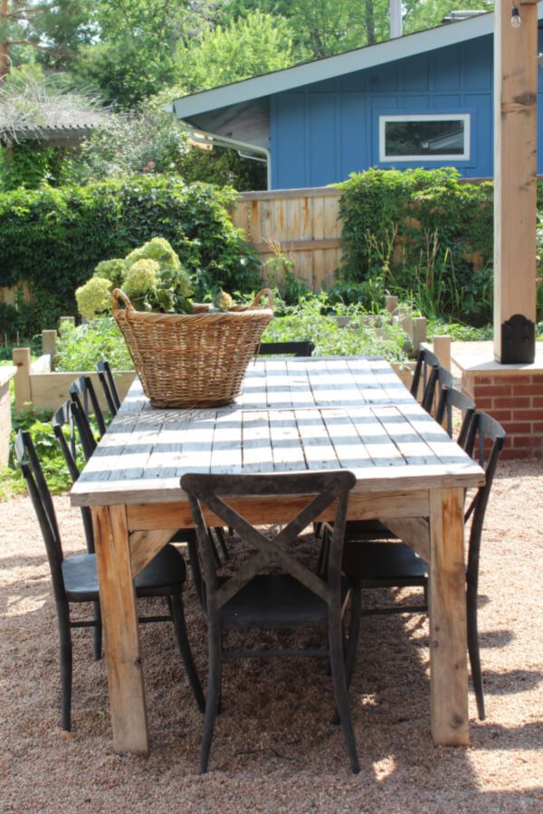 black metal x back chairs flanking a wooden table in our backyard dining space.