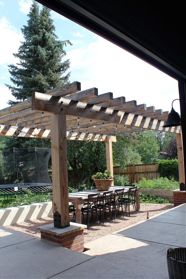 Outdoor dining perfection with pergola, cafe lights and wooden table.
