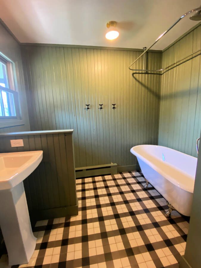 Kid bathroom with green bead board walls and vintage claw foot tub.