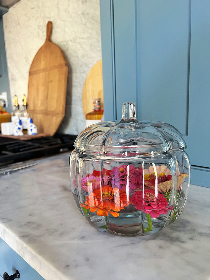 Glass lidded pumpkin full of zinnias