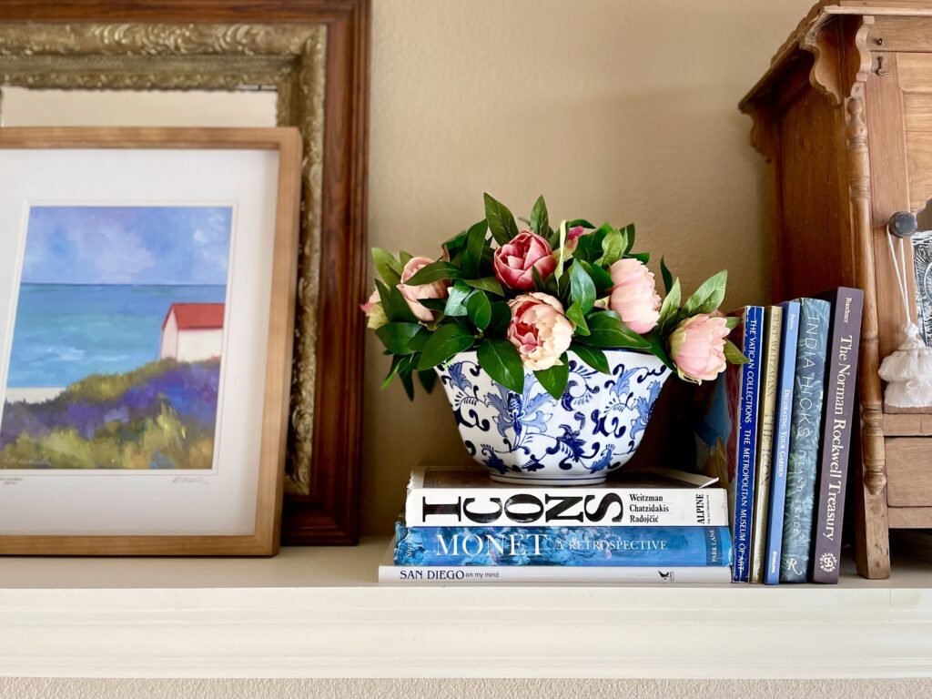 faux spring peonies on mantel in bowl with books